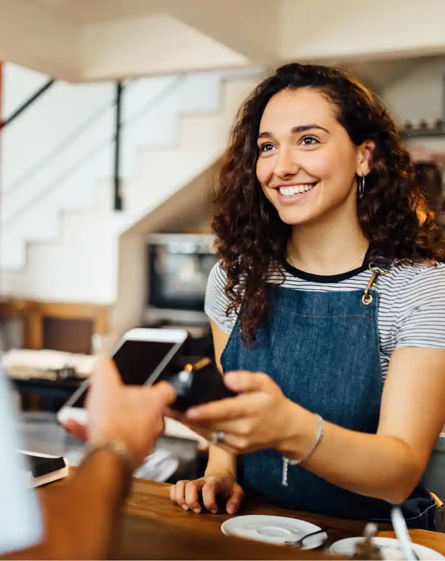 Una barista recibe el pago de su cliente