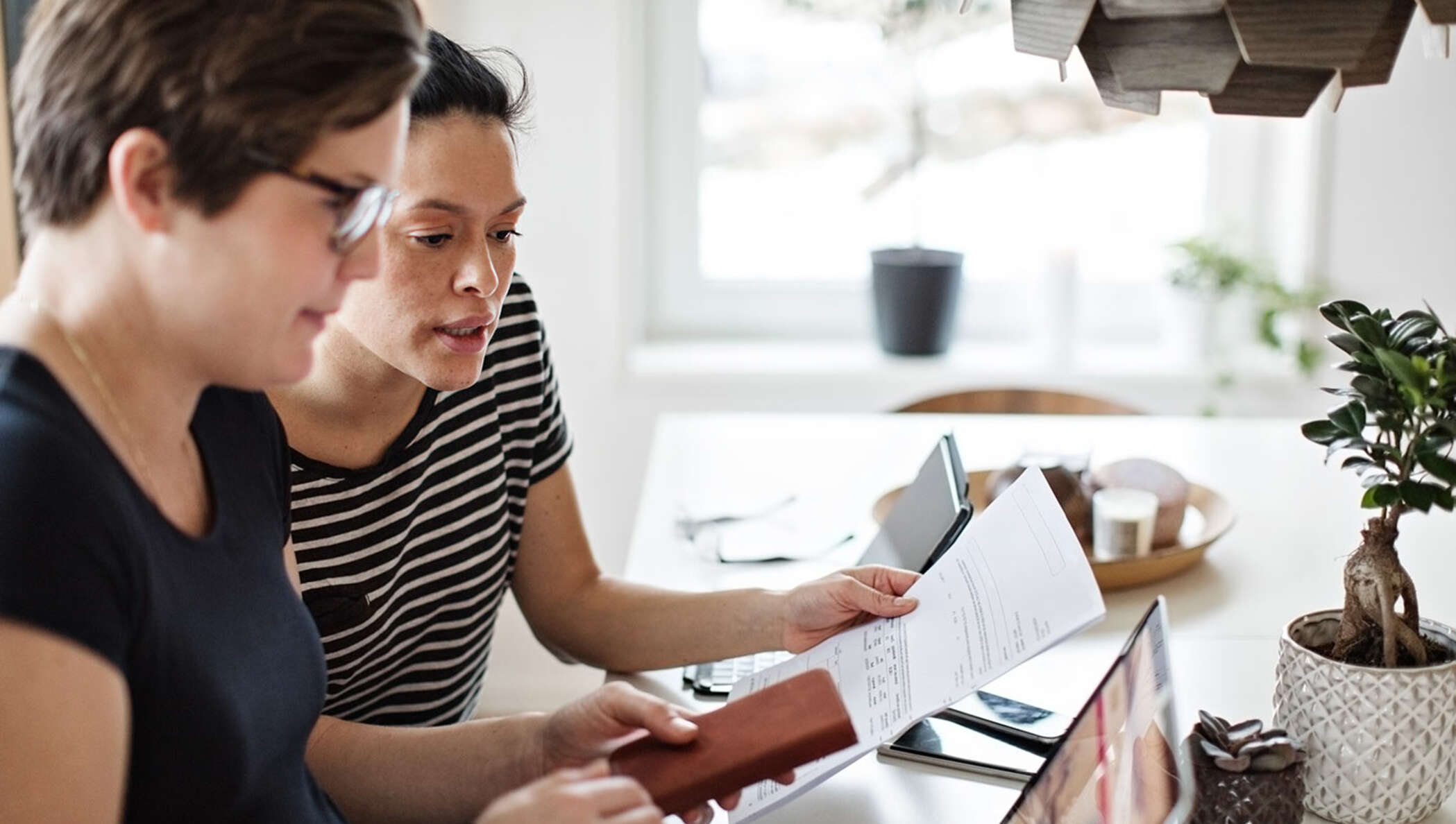 A couple discussing paperwork while using laptop at table