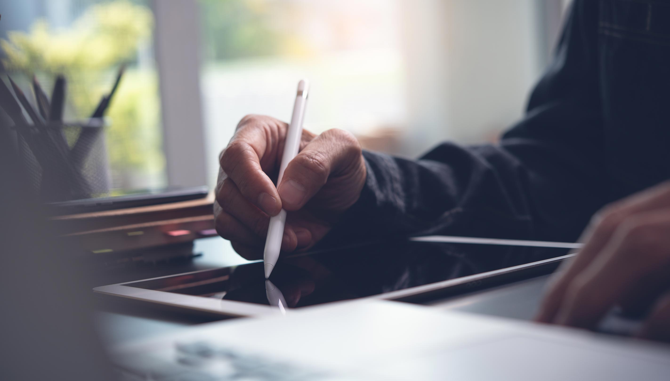 Man at desk using a tablet with a stylus pen.