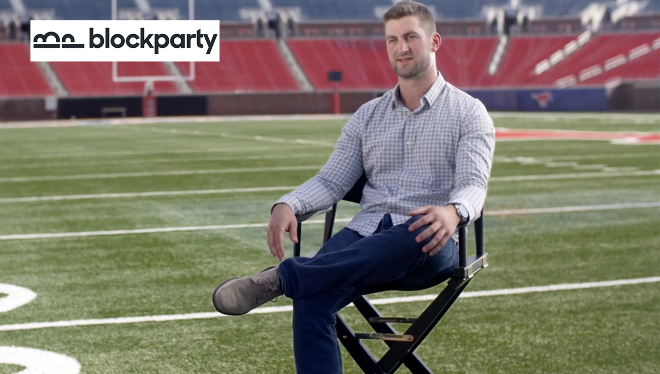 A man on a directors chair on a football field.